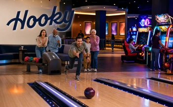 A diverse family and friends bowling beside colorful arcade games at Hooky Entertainment Homestead.